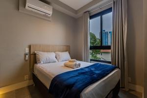 une chambre avec un lit avec une grande fenêtre dans l'établissement Studios Vila Madalena com Ar condicionado | Delfhy, à São Paulo 144 autres photos