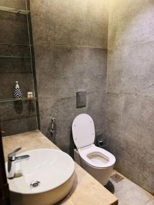 une salle de bain avec des toilettes blanches et un lavabo dans l'établissement Blue Sapphire Forest Stays, à Ghaziabad