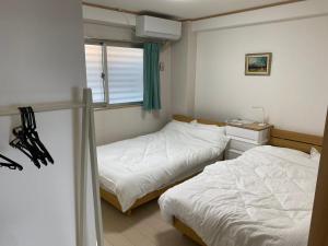 een slaapkamer met twee bedden en een raam bij ホワイトヒルズ in Tomigusuku