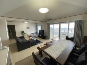 een woonkamer met een eettafel en een bank bij ホワイトヒルズ in Tomigusuku