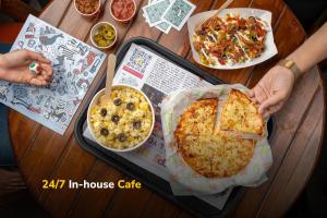 a person holding a pizza on a table at goSTOPS Kasol in Kasol