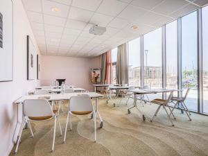 a classroom with tables and chairs and large windows at Mercure Dunkerque Centre Gare in Dunkerque