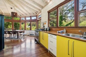 cocina con armarios amarillos y comedor con mesa en The Mud Brick House, en Leura