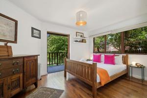 Un dormitorio con una cama con almohadas rosas y una ventana. en The Mud Brick House, en Leura