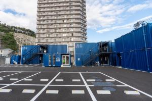 勝浦市にあるHOTEL R9 The Yard Katsuraの青いコンテナと高い建物のある駐車場