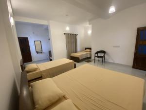 a room with two beds and a chair in it at Misty Clouds Homestay in Kandy