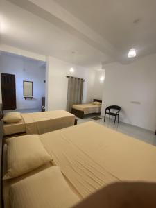a room with three beds and a chair in it at Misty Clouds Homestay in Kandy