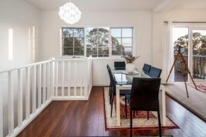 Un comedor con mesa y sillas y ventanas. en La Cachette in Upwey 3BR Retreat with Mountain Views, en Upwey