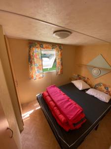 een klein bed in een kleine kamer met een raam bij CAMPING de la BUGE in Rochefort-Montagne