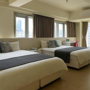 duas camas num quarto de hotel com janelas em Music City Inn em Kaohsiung