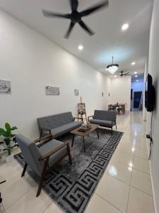 a living room with couches and a ceiling fan at Hasya Guesthouse in Seri Iskandar