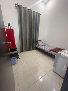 a small room with a bed and a curtain at Hasya Guesthouse in Seri Iskandar