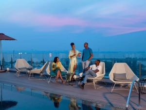 a group of people sitting on the edge of a swimming pool at Novotel Kinshasa La Gombe in Kinshasa