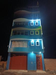a tall blue building with red doors at night at Hostal JM in Huancayo