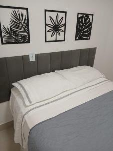 Una cama en un dormitorio con cuatro cuadros en la pared. en Apartamento á 1200m da Praia de Itapua, en Vila Velha