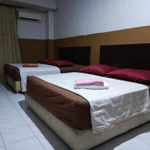 two beds with towels on them in a room at Meple Hotel Skudai in Skudai