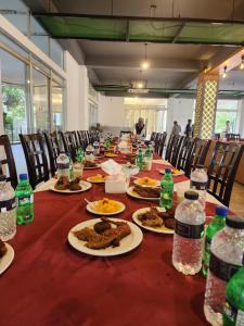 un lungo tavolo con piatti di cibo e bottiglie d'acqua di Aristocrat Resort Purbachal a Pānjora