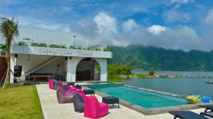 a swimming pool with pink chairs next to the water at Lushy Hostel Kintamani in Kubupenlokan