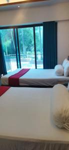 due letti in una stanza d'albergo con finestra di Aristocrat Resort Purbachal a Pānjora Altre 32 foto