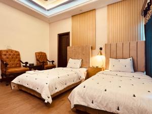 een slaapkamer met 2 bedden en een stoel bij Crest View Guest House Islamabad in Islamabad