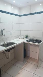 Una cocina blanca con fregadero y estufa. en Apartamento á 1200m da Praia de Itapua, en Vila Velha