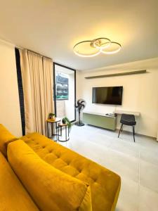 a living room with a yellow couch and a television at Confort total 2 Habitaciones, AC y excelente ubicación in Floridablanca