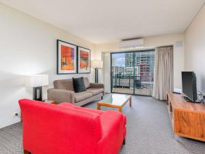 a living room with a couch and a red chair at Mantra on Hay Perth in Perth