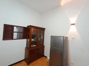 a kitchen with a refrigerator and a wooden cabinet at Villa Piore in Mirissa