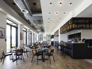 a restaurant with tables and chairs and a bar at Mantra MacArthur Hotel in Canberra