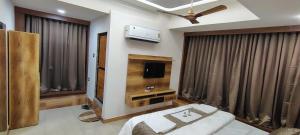 a living room with a couch and a tv and curtains at Hotel The Grand Heritage Junagadh in Junagadh