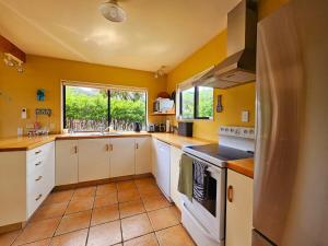 a kitchen with yellow walls and white cabinets at Tatahiti Haven - Sea Views & Classic Kiwi Charm in Tata Beach +7 photos