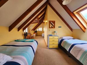 a attic bedroom with two beds and a desk at Tatahiti Haven - Sea Views & Classic Kiwi Charm in Tata Beach