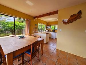 a kitchen and dining room with a wooden table and chairs at Tatahiti Haven - Sea Views & Classic Kiwi Charm in Tata Beach