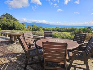 a wooden table and chairs on a deck at Tatahiti Haven - Sea Views & Classic Kiwi Charm in Tata Beach