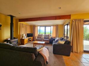 a living room with two couches and a television at Tatahiti Haven - Sea Views & Classic Kiwi Charm in Tata Beach