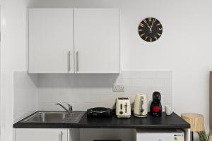 a kitchen with a sink and a clock on the wall at Bright and Cozy Studio Flat for a Relaxing Stay in Greenford +7 photos