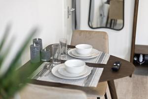a wooden table with two cups and plates on it at Bright and Cozy Studio Flat for a Relaxing Stay in Greenford