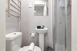a bathroom with a toilet and a sink and a shower at Bright and Cozy Studio Flat for a Relaxing Stay in Greenford