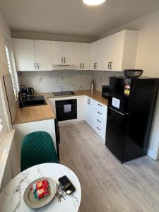a small kitchen with a black refrigerator and a table at Stylish Haven with a Touch of Colour - Hosted by Canstay in Downer