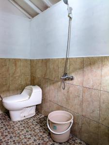 a bathroom with a toilet and a bucket at Kampung Bareto Cottage And Resto in Tjisurupan