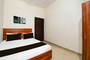 a bedroom with a bed with a wooden headboard at Hotel O Sultanpur Railway Junction Formerly Sanskar Marriage Lawan in Sultānpur