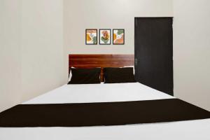 a bedroom with a large bed with a black headboard at Hotel O Sultanpur Railway Junction Formerly Sanskar Marriage Lawan in Sultānpur +13 photos