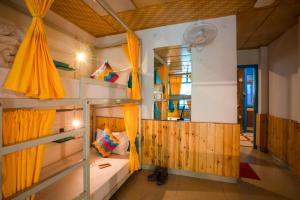 une chambre avec deux lits superposés et des rideaux orange dans l'établissement goSTOPS Kasol, à Kasol