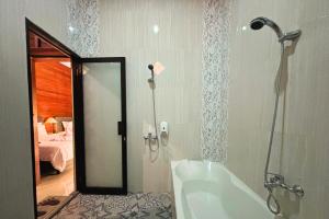 a bathroom with a shower and a bath tub at Arisa Villa by AGATA in Menanga +22 photos