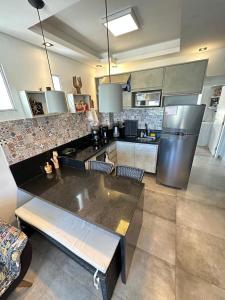 a large kitchen with a counter and a refrigerator at Casa de boneca em Condomínio - Juquehy in São Sebastião