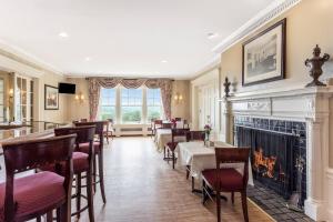 a dining room with tables and chairs and a fireplace at Traditions Hotel & Spa Johnson City - Binghamton, an Ascend Collection Hotel in Johnson City