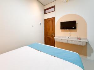 ein Schlafzimmer mit einem Bett und einem Flachbildfernseher in der Unterkunft Sans Stay Harmoni 88 Ambarukmo Plaza Yogyakarta in Adi Sutjipto