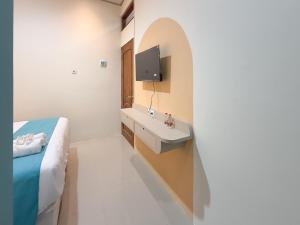 ein Bad mit einem Waschbecken, einem Bett und einem TV in der Unterkunft Sans Stay Harmoni 88 Ambarukmo Plaza Yogyakarta in Adi Sutjipto + 34 Fotos