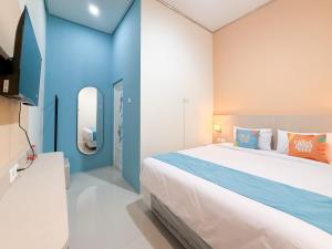 ein Schlafzimmer mit einem großen Bett und einer blauen Wand in der Unterkunft Sans Stay Harmoni 88 Ambarukmo Plaza Yogyakarta in Adi Sutjipto