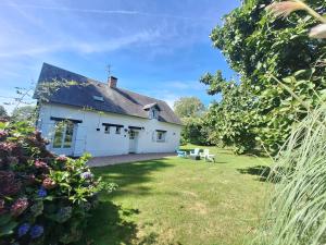a white house with a yard with a bench at Gîte Le Bon Normand in Ã‰tainhus
